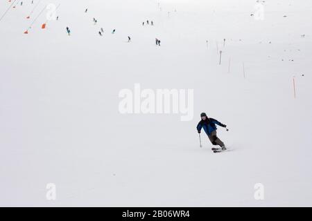 Stazione sciistica. Lo sciatore scende rapidamente su una pista professionale coperta di neve. Neve bianca. Persone dietro. Sport professionale. Foto Stock