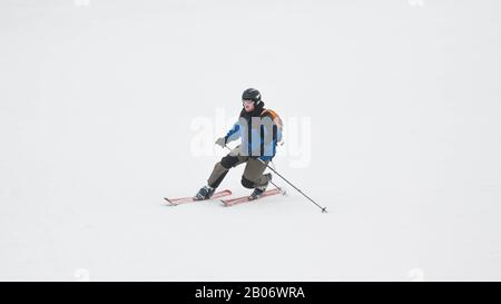 Stazione sciistica. Lo sciatore scende rapidamente su una pista professionale coperta di neve. Neve bianca. Sport professionale. Foto Stock