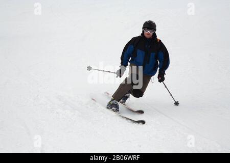 Stazione sciistica. Lo sciatore scende rapidamente su una pista professionale coperta di neve. Neve bianca. Sport professionale. Foto Stock