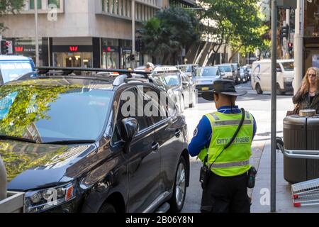 Ranger del consiglio dell'Australia nel centro di sydney che mette il biglietto del parcheggio su un'automobile parcheggiata illegalmente, Sydney, Australia Foto Stock