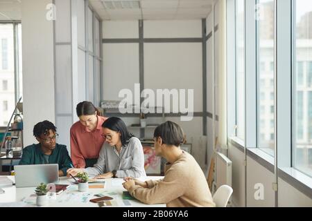 Giovani imprenditori seduti al tavolo e pianificare insieme un nuovo progetto durante la giornata lavorativa in ufficio Foto Stock