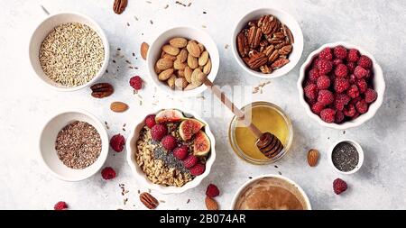 Ingredienti per una colazione sana, farinata d'avena con lamponi, fichi, noci pecan, mandorle, semi di lino, semi di chia con miele e caffè. Buongiorno, guarite Foto Stock