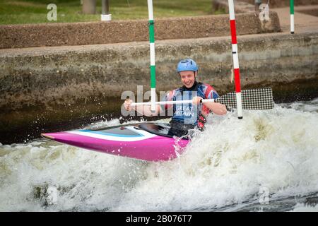 Molto felice GB Canoe Slalom Athlete che negozia un cancello a monte su un'onda. Classe C1W - Donna. Foto Stock