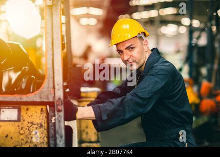 Ritratto di operatore di fabbrica caucasica bello intelligente con abiti di sicurezza e casco giallo. Foto Stock