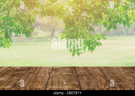 Tavolo in legno su sfocatura abstract verde albero giardino in background mattina. Parco naturale per montaggio prodotto display o design chiave layout visivo Foto Stock