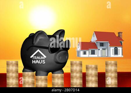 Banco piggy nero con occhiali da sole con scritta Traumhaus, sogno di possedere una casa, casa, tramonto e pila di monete in background, composizione Foto Stock