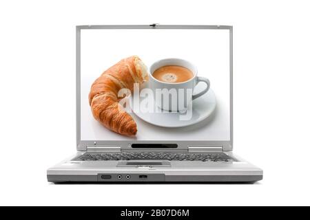 laptop che mostra il breakfirst con croissant e caffè sul display Foto Stock