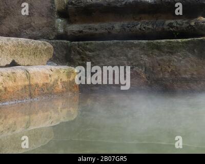 Il vapore che sale galleggia attraverso l'acqua di sorgente del Grande bagno nelle storiche Terme Romane, Città di Bath, Somerset, Regno Unito Foto Stock