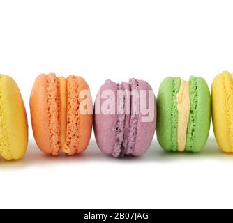 torte di macaron tondi multicolori su sfondo bianco isolato, stand dessert in fila, primo piano Foto Stock