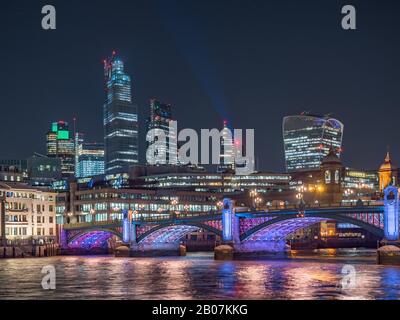 Vista panoramica notturna del Tamigi con ponte Southwark e quartiere finanziario sullo sfondo. Paesaggio Urbano Di Londra, Regno Unito Foto Stock