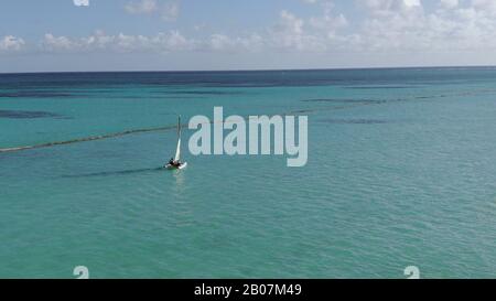 Un piccolo catamarano naviga in acque turchesi al largo di Punta Cana, nella Repubblica Dominicana. Sport acquatici e divertimento all'aperto nel Mar dei Caraibi. Foto Stock