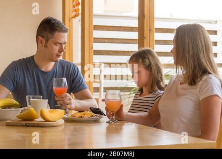 Papà è arrabbiato con sua figlia che non mangia, ma gioca un computer. Foto Stock