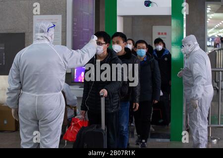 Gli operatori sanitari cinesi ben attrezzati controllano le temperature del corpo dei passeggeri all'uscita per prevenire il nuovo coronavirus e la polmonite sulla loro A. Foto Stock