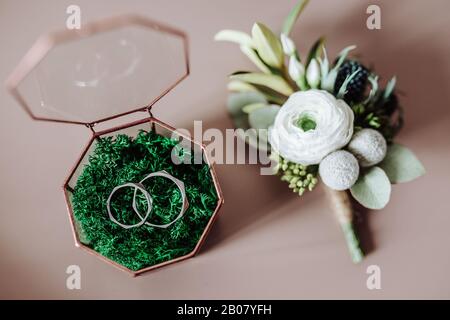 Decorazioni di nozze per la sposa e lo sposo. Boutonniere e anelli sul tavolo Foto Stock