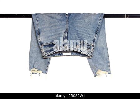 un paio di jeans piegati su rotaia nera su sfondo bianco, illuminazione da studio Foto Stock