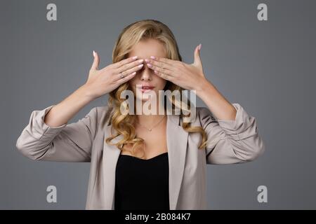 Ritratto di bella donna chiude gli occhi con la mano su sfondo grigio. Non riesco a vedere Foto Stock