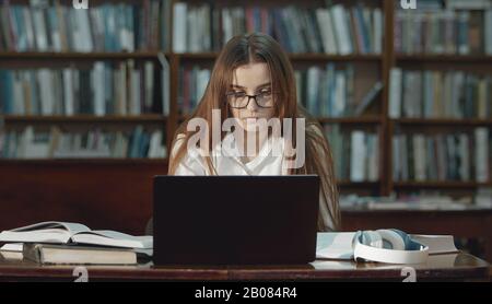 Portatile di lavoro adolescente in biblioteca Foto Stock