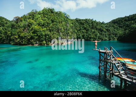 L'uomo medita alla laguna al mattino, godendo della vista. Colpo alla baia di sugba in Siargao, filippine Foto Stock