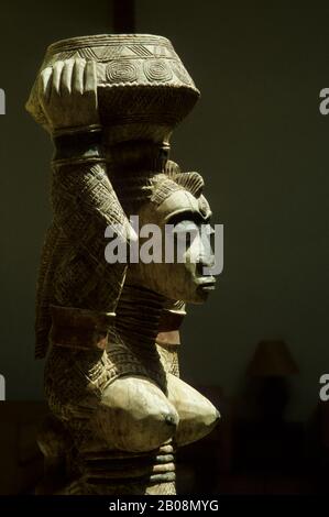 Una scultura in legno tribale Dogon di una donna che porta un cesto viene venduta in un negozio a Dakar, Senegal, Africa occidentale Foto Stock
