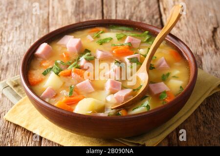 Portata di zuppa di piselli spezzata con prosciutto da vicino in una ciotola sul tavolo. Orizzontale Foto Stock