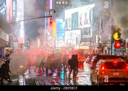 Il vapore che deriva circonda la gente, il traffico e gli edifici Di Times Square nella notte innevata a Midtown Manhattan New York City NY USA il 18 gennaio 2020 Foto Stock