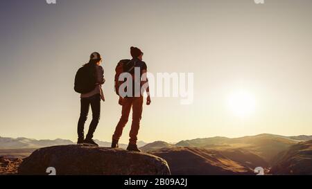 Due viaggiatori o escursionisti sono in piedi al tramonto su grande roccia in montagna zona Foto Stock