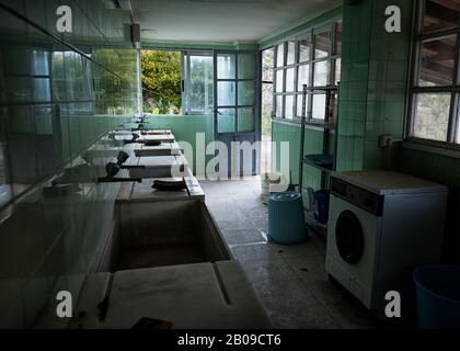 Vecchia lavanderia di Sanatorio Fontilles con rubinetti d'epoca, lavatrice e lavabi in marmo (Fontilles, Vall de Laguart, Marina alta, Alicante, Spagna) Foto Stock