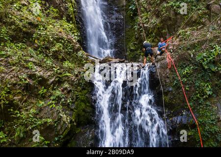 Avventura turismo in Costa Rica tropicale con un giovane uomo che rapina giù una bella cascata profonda nelle montagne meridionali del paese Foto Stock