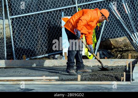 Impresa edile in cemento che installa una canalina di drenaggio per marciapiedi, marciapiedi e temporali su una nuova costruzione della casa. Foto Stock