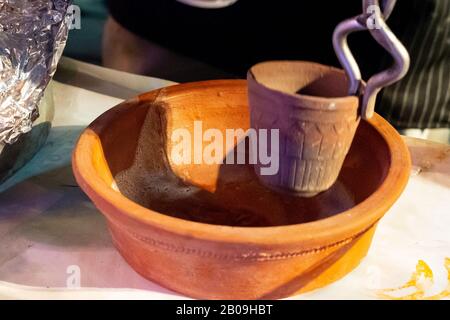 Fornitore indiano di cibo di strada che fa tandoori masala chai tè bollendo in una pentola calda di argilla in pentola di ottone per bollire il tè Foto Stock