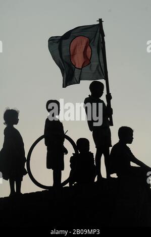 Silhouette di bambini con la bandiera nazionale in occasione del Victory Day o Bijoy Dibash del Bangladesh. Bijoy Dibash commemora il giorno nel 1971 (16 dicembre) quando 90.000 truppe delle forze di occupazione pakistane si arresero alle forze alleate del Bangladesh e dell'India a Suhrawardy Udddddyan a Dhaka, terminando una guerra di liberazione contro il Pakistan lunga nove mesi. Dhaka, Bangladesh. 16 Dicembre 2008. Foto Stock