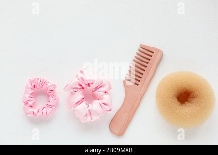 Spazzolina in legno, barrette e scorconcino rosa isolato su bianco. Strumenti E accessori Per Acconciature a disposizione piatta per capelli colorati Scrunchies, capelli Elastici Foto Stock