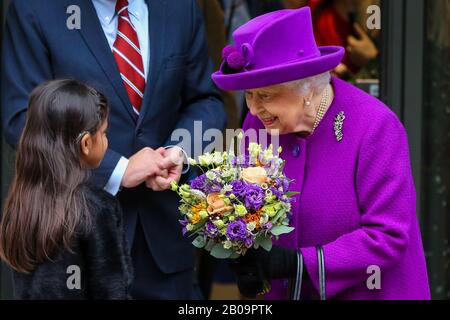 Una giovane ragazza dà fiori alla regina Elisabetta II mentre lascia il Royal National Throat, l'ospedale Naso e orecchio e l'Eastman Dental Hospital nel centro di Londra dopo l'apertura della nuova sede. Foto Stock