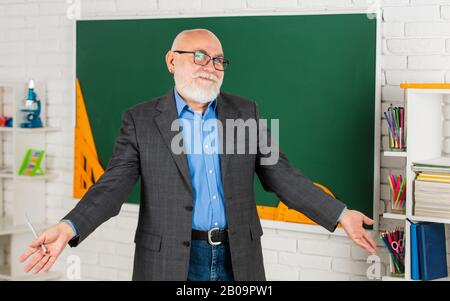 Insegnante di uomo intelligente senior presso la lavagna. Insegnante di vecchia generazione della scuola. Docente esperto. Insegnante maturo buon insegnamento. Condivisione delle conoscenze. Ottenere certificazioni per programmi specifici. Foto Stock