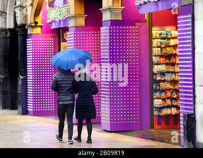 Londra, Inghilterra, Regno Unito. Un paio di persone passeggiano davanti al Regno degli svedesi a Piccadilly Circus in una giornata di pioggia Foto Stock