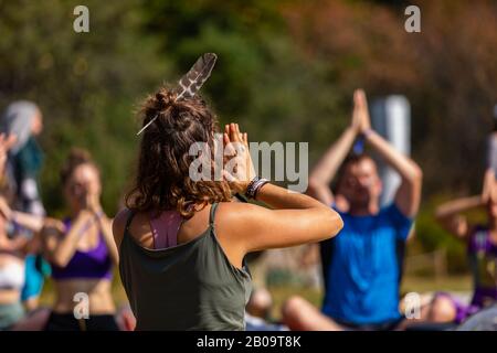 Un coach spirituale di consapevolezza e benessere è visto in fuoco selettivo, insegnando alle persone anjali mudra, una postura centrante della mano. Copiare lo spazio a destra Foto Stock