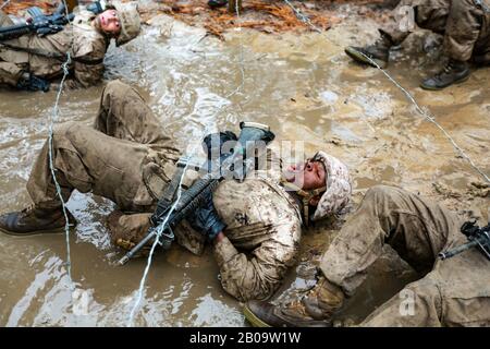 Il corpo dei Marine degli Stati Uniti recluta con Delta Company, 1st Recluta la manovra di battaglione di addestramento attraverso fango e filo spinato durante il corso Di Endurance Di Combattimento 21 dicembre 2019 al deposito Di Reclutamento del corpo dei Marine Isola di Parris, Carolina del Sud. Foto Stock