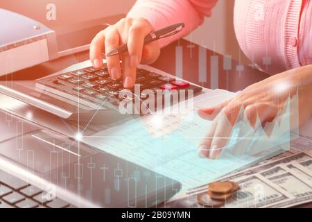 La ragazza contabile in ufficio guarda i dati nel documento e li controlla usando una calcolatrice. Analisi del mercato e del profitto, calcolo delle imposte Foto Stock