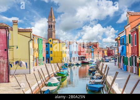 Paesaggio con case colorate, canale, barca e chiesa sulla famosa isola di Burano, Venezia, Italia Foto Stock