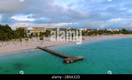 Paradiso tropicale spiaggia, sabbia bianca, palme e molo di legno, molo nel resort di lusso Caraibi, moderno resort di vacanza sullo sfondo, Punta Cana Foto Stock