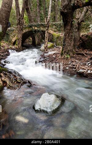 Bellissimo ponte medievale o Milia con fiume pieno di acqua che scorre sulle montagne di Troodos a Cipro Foto Stock