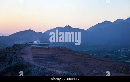 Alba su una piccola cappella in cima alle colline che si affacciano Panormos ( non mostrato ) a Creta con montagne sullo sfondo Foto Stock