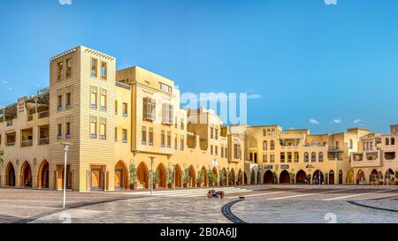 Famiglia seduto in una grande piazza vuota al tramonto, New Marina, El Gouna, Egitto, 17 gennaio 2020 Foto Stock