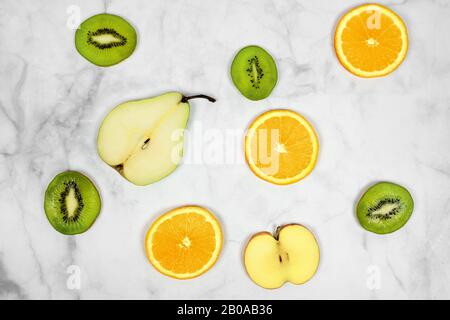 frutta a fette pera kiwi mela arancione con sfondo marmo minimalista. Foto Stock