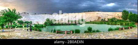 Pamukkale, Turchia – 07.14.2019. Montagna bianca e lago verde a Pamukkale. Vista panoramica dal lato del villaggio in una serata estiva nuvoloso. Foto Stock