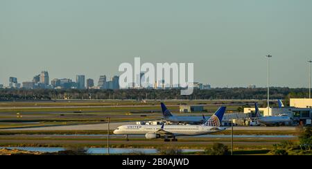 United Airline Airplanes all'Aeroporto Internazionale di Orlando con lo skyline del centro cittadino di Orlando sullo sfondo. Foto Stock