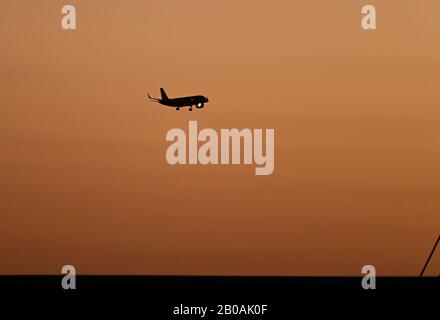 Un aereo atterra all'Aeroporto Internazionale di Orlando al tramonto. Foto Stock