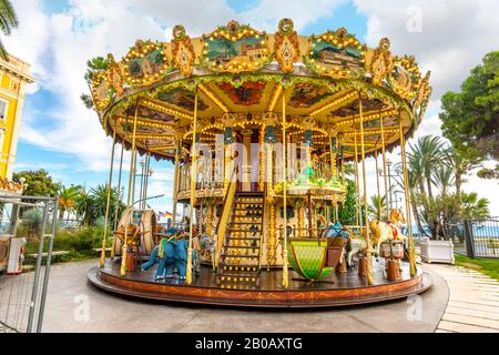 La giostra colorata e allegra si girò intorno all'Albert i Garden con il mare blu alle spalle, sulla Riviera Francese a Nizza, Francia Foto Stock