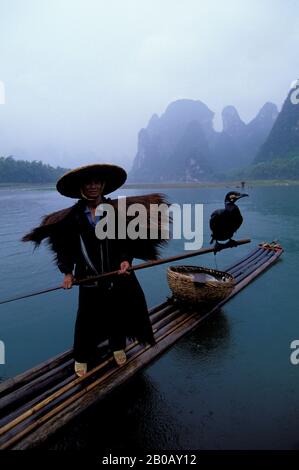 CINA, PROVINCIA DI GUANGXI, VICINO GUILIN, XING PING, FIUME LI, PIOGGIA, PESCATORE SU ZATTERA DI BAMBÙ, CORMORANI Foto Stock