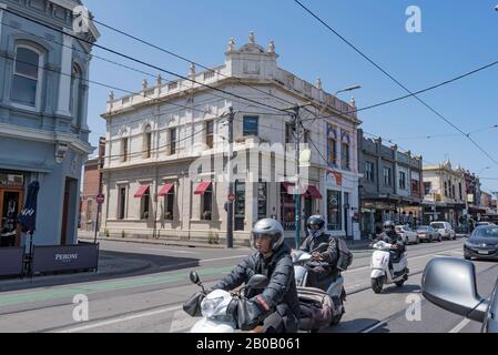 Gli scooter a motore si fermavano nel traffico su Chapel Street vicino a Eastbourne Street e di fronte ai negozi di vendita al dettaglio a due piani in tardo Vittoriano a Prahran, Aust. Foto Stock